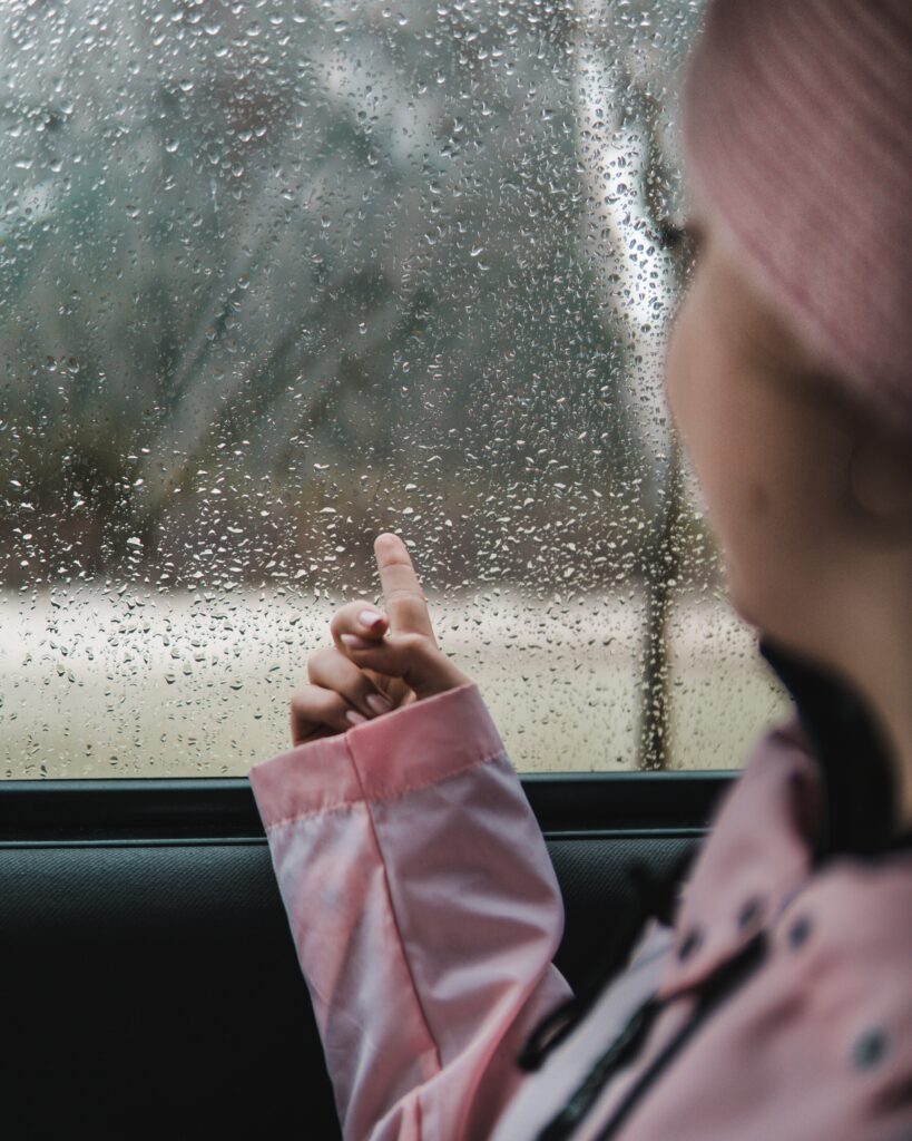 車内の窓ガラスについた水滴をなぞる子供