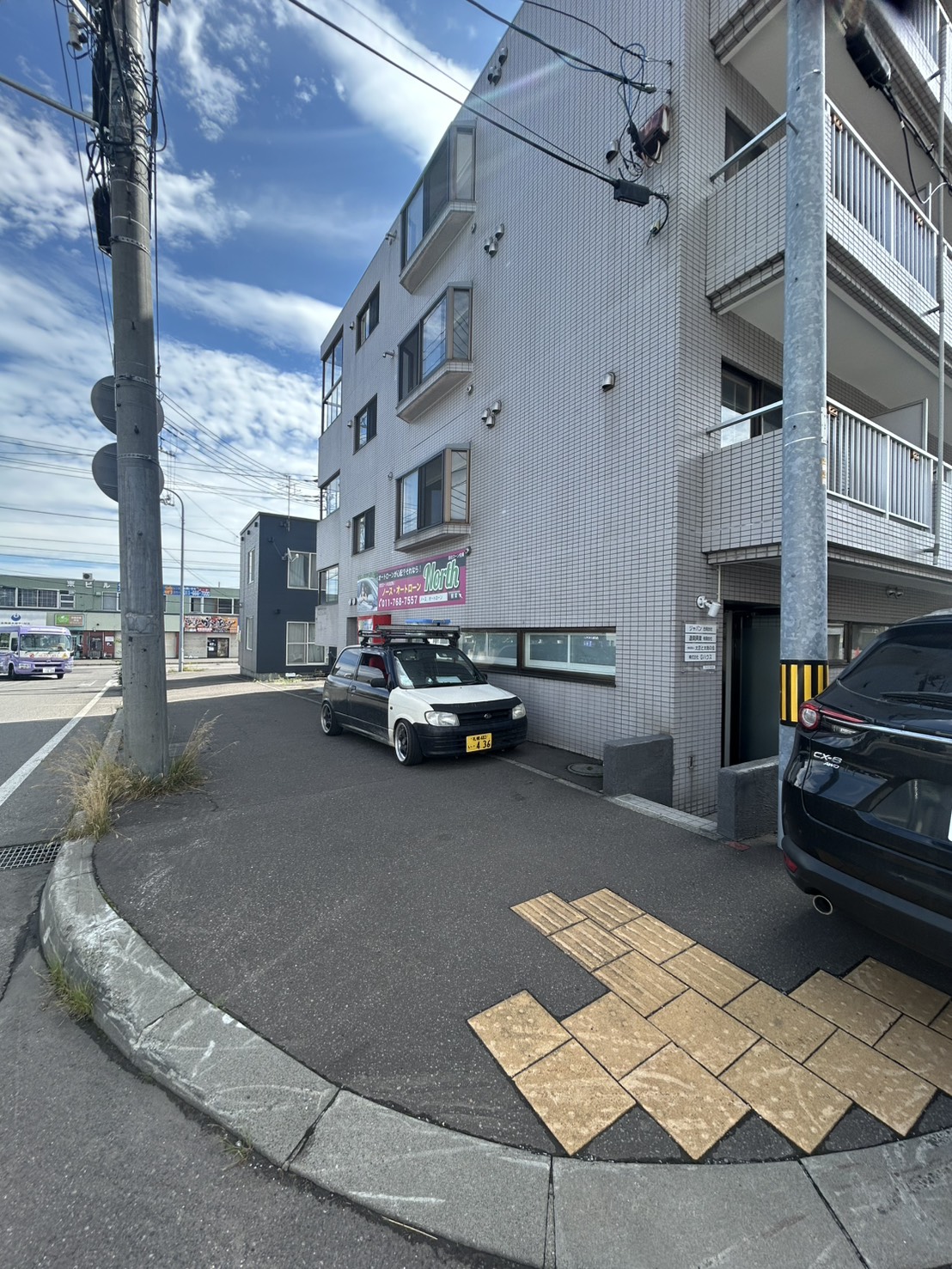 ジャパン合同会社が入る札幌市西区のビル外観。道路に面した建物と駐車スペース