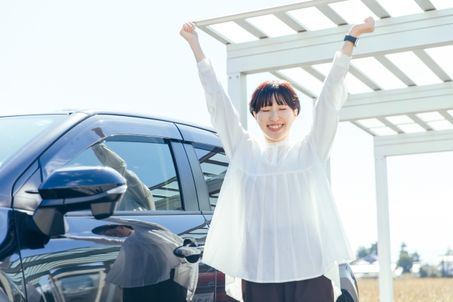 車の横で喜ぶ若い女性