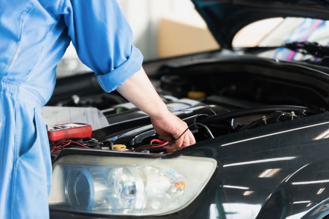 車のエンジンルームを確認する整備士