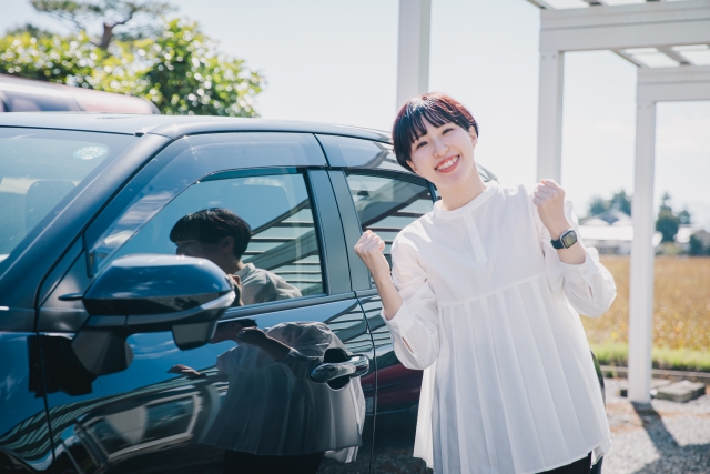 車の前で喜ぶ女性