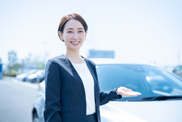 並んだ中古車を案内するスタッフ