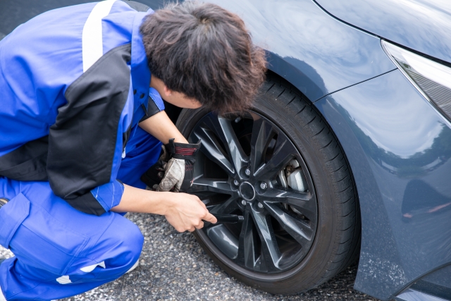 青い作業着の整備士がタイヤ周りを確認する様子